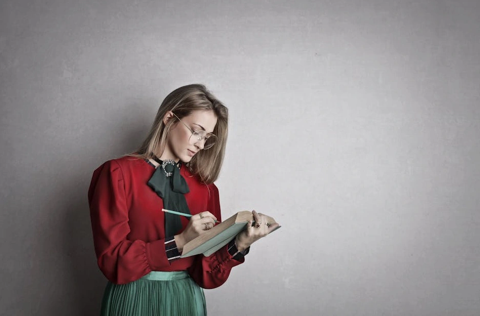Osoba si zapisuje cíle do poznámkového bloku na pracovním stole.